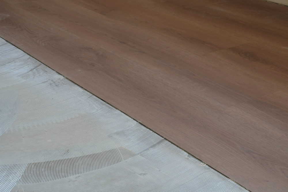 Teilweise verlegtes Laminat auf frisch aufgetragenem Fliesenkleber beim Laminat verlegen
