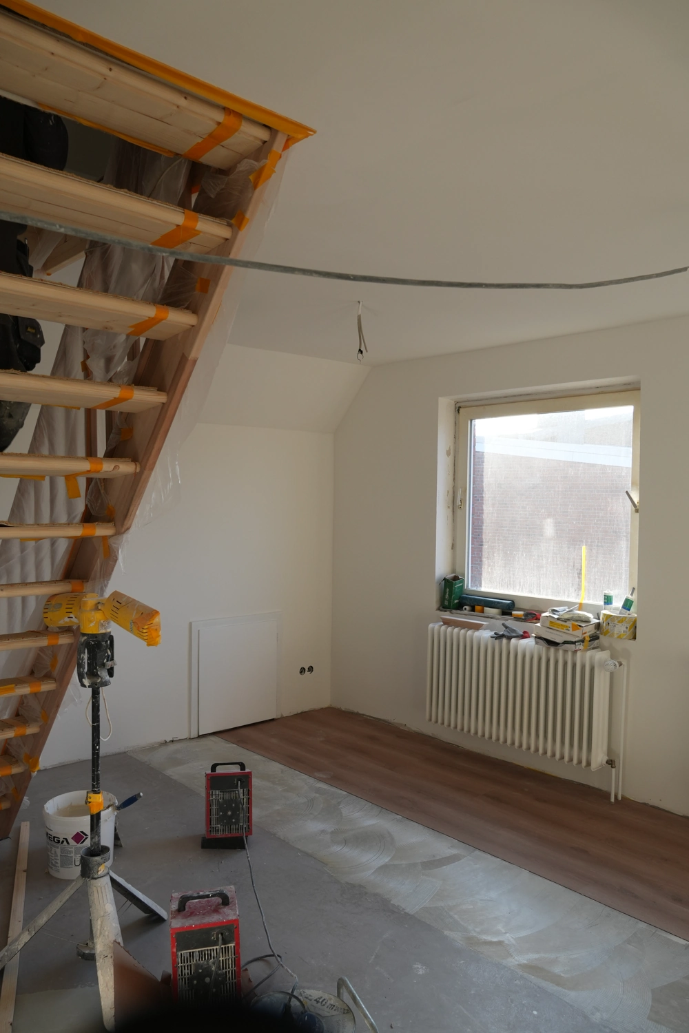 Dachgeschossausbau: unfertiger Dachraum mit neuer Treppenkonstruktion und vorbereitetem Laminatboden