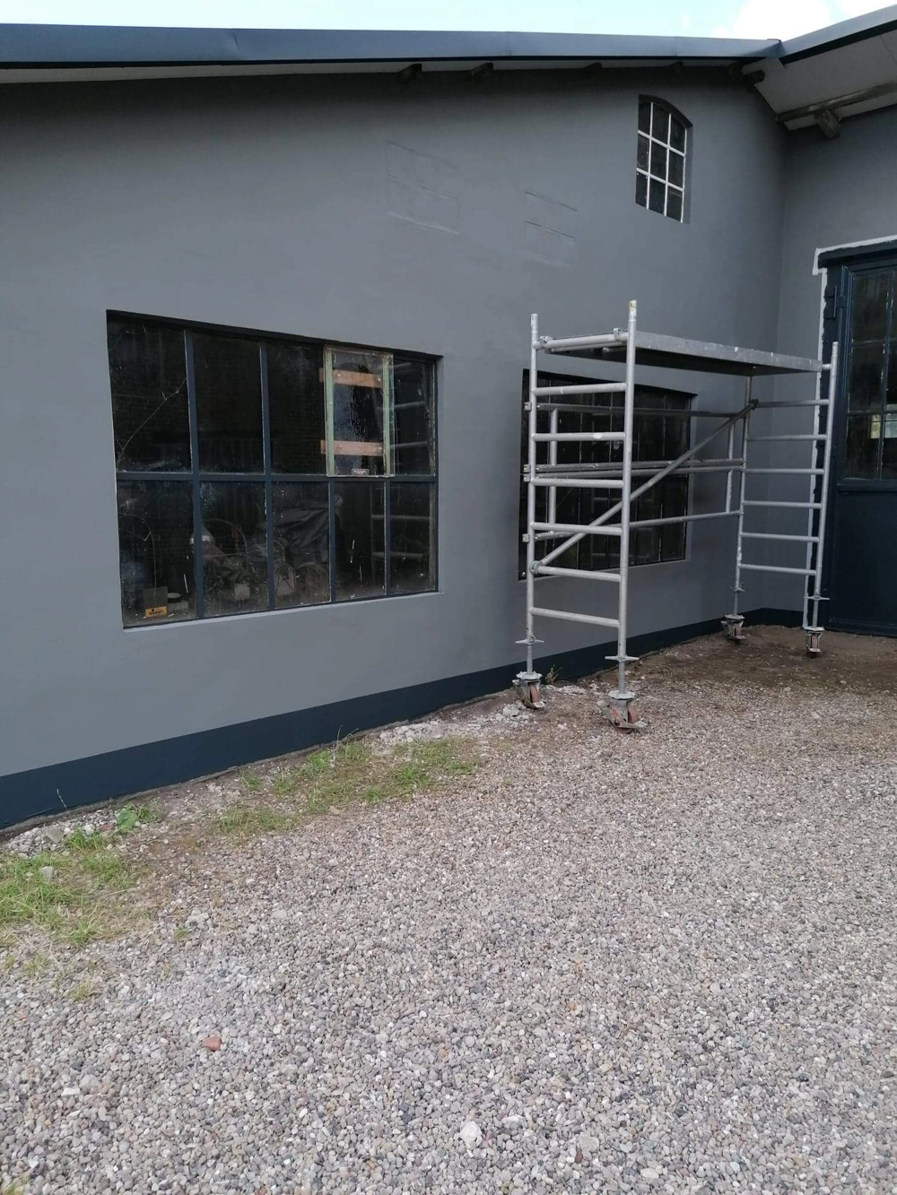 Gerüst vor frisch verputzter Fassade mit Industrie-Fenstern, Fassadensanierung