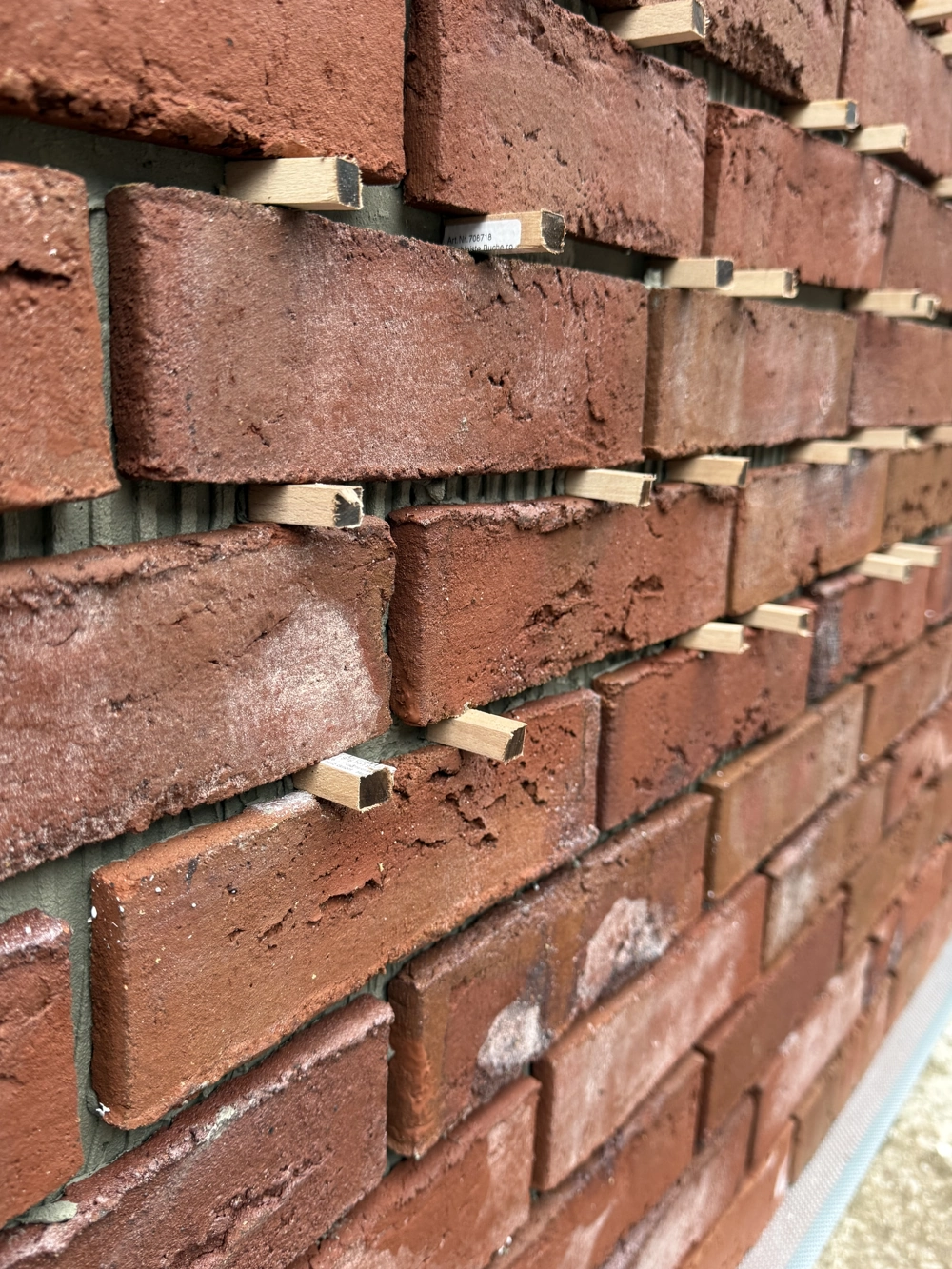 Rote Klinkerriemchenfassade mit Holzkeilen zur gleichmäßigen Fugenverteilung