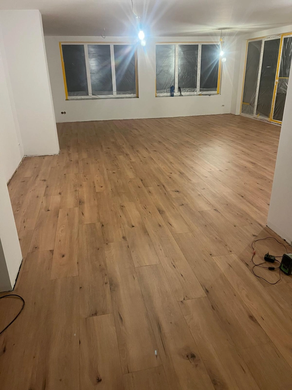 Leerstehender Raum mit frisch verlegtem Laminatboden und weißen Wänden