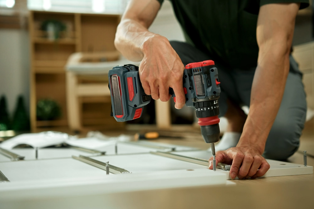 Handwerker montiert Möbelbauteil mit Akkuschrauber auf Boden