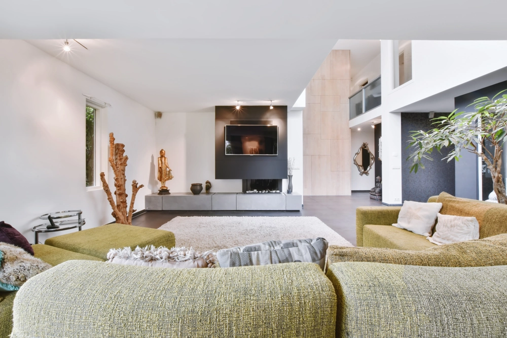 Modernes Wohnzimmer nach Wohnungsrenovierung mit grünem Ecksofa, Flachbildfernseher, Teppich und Dekoobjekten