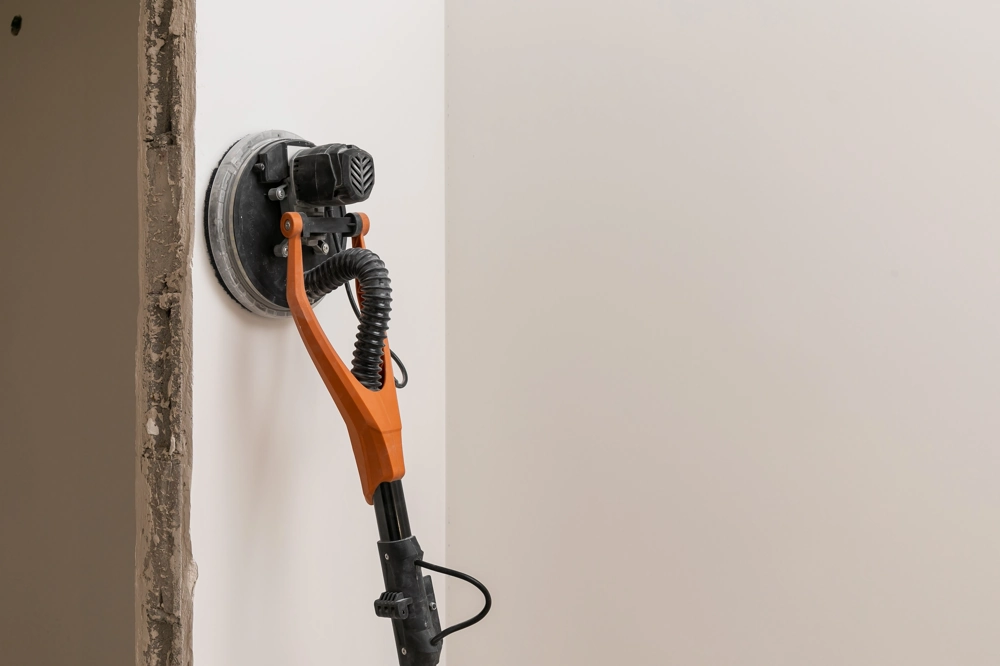 Wandschleifer bei Spachtelarbeiten zum Glätten der gespachtelten Innenwand neben einem Türrahmen