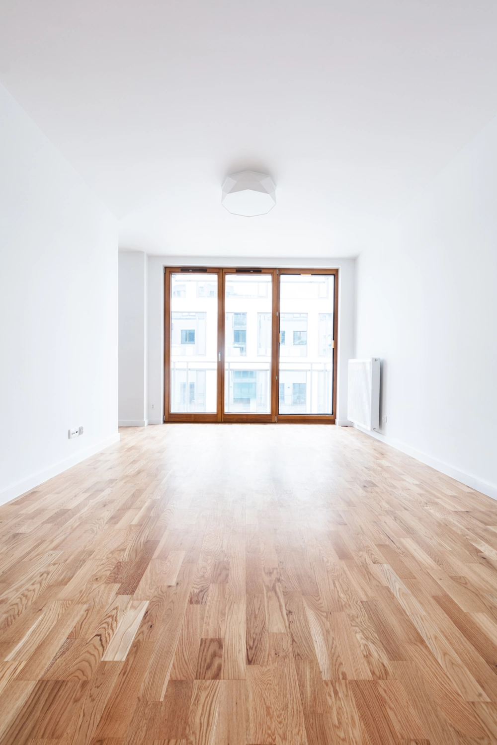 Frisch durchgeführtes Parkett verlegen in hellem Raum mit Holzboden, weißen Wänden und großen Holzfenstern