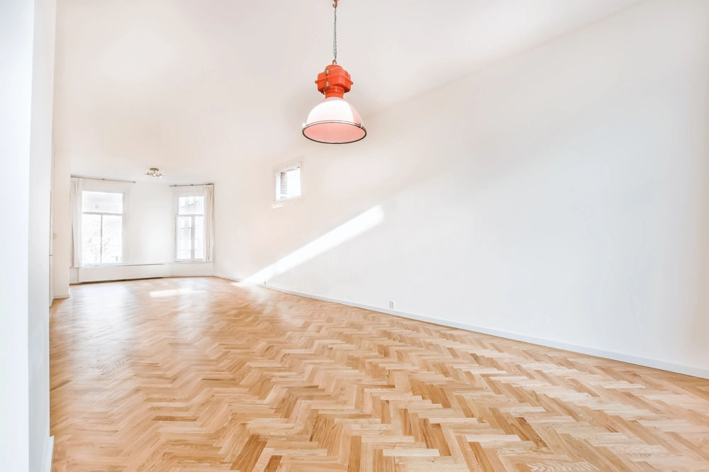 Heller, großer Raum mit verlegtem Fischgrätparkett und weißen Wänden – Parkett verlegen