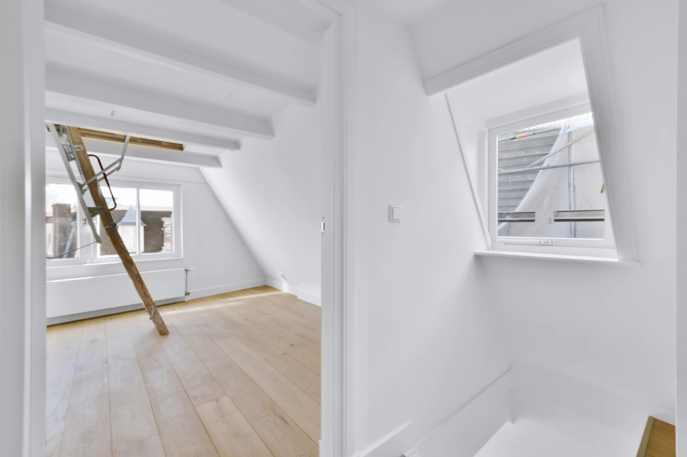 Ausgebautes Dachgeschoss mit frisch verlegtem Parkettboden und Zugang über Dachbodenleiter