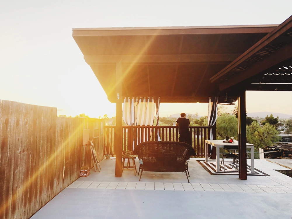 Holz-Gartenpavillon mit Sitzbereich, Vorhängen und Terrassenboden bei Sonnenuntergang