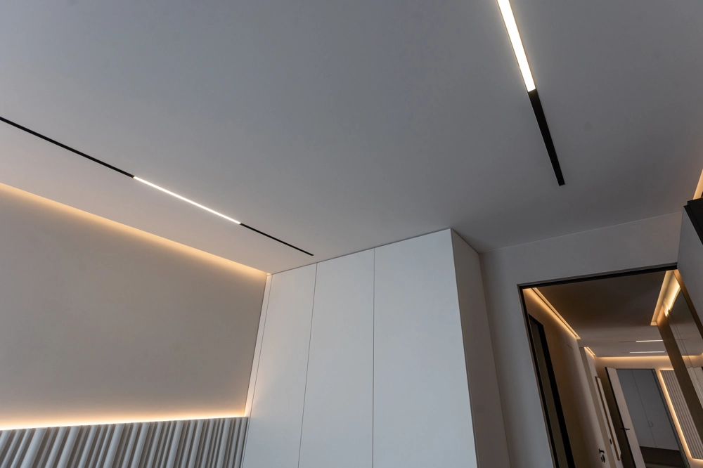 Abgehängte Decken mit integrierten LED-Leisten in modernem Innenraum mit weißem Einbauschrank und Flur